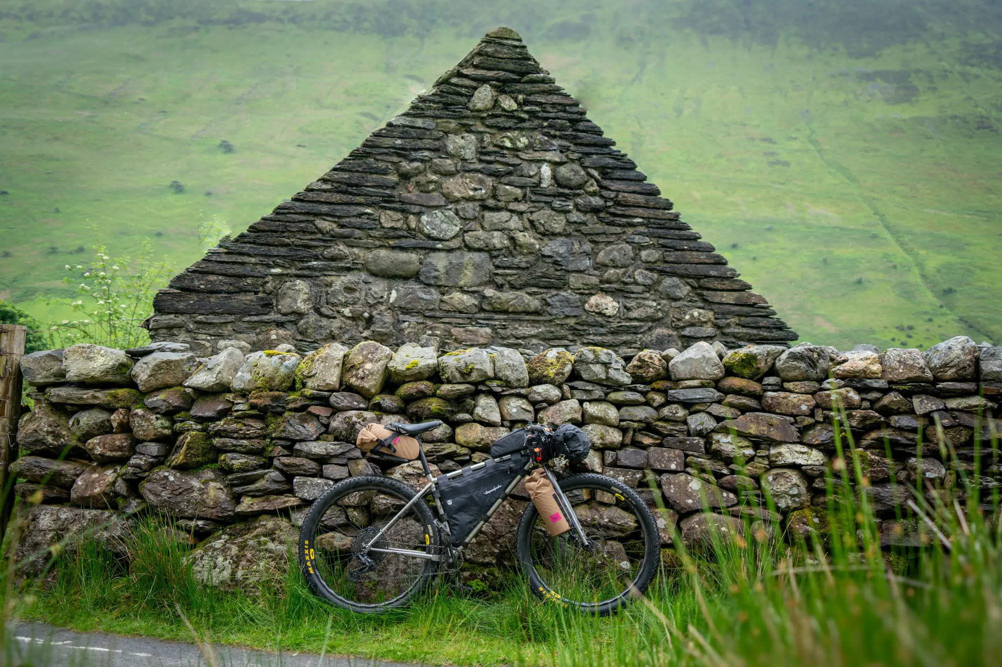 The bike leaning against a stone fence.
